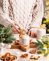 White cups of hot cocoa with whipped cream decorated with gingerbread man.