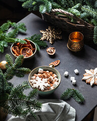 Green cup of hot cocoa with marshmallow decorated with mini gingerbread snowflake.