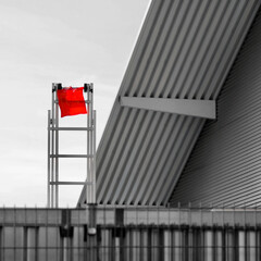 Aluminiumleiter mit rotem Tuch an der Spitze steht angelehnt an einem Industriegebäude