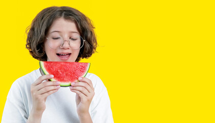 funny teenage girl with glasses enjoys slice of juicy red watermelon on colored background, copy space