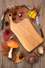 Composition with fly amanita near cutting board and surrounding forest items on wooden table upper view. Microdosing for psychotherapy improvement