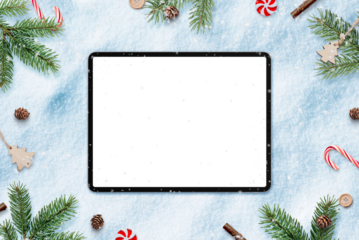 Tablet in snow for app design or copy promotion. Surrounded by Christmas decorations. Top view, flat lay