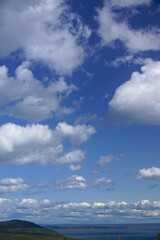 Fototapeta premium Fundy National Park, New Brunswick, Canada: Bright blue sky with fluffy white clouds over the Bay of Fundy at high tide.