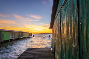 Bootshütten mit Steg zu Sonnenaufgang in Plau am See in Mecklenburg-Vorpommern - obrazy, fototapety, plakaty
