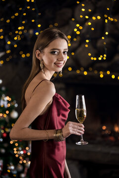 A girl in an evening dress with a glass of champagne on the background of New Year's lights