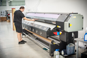 In the printing house, an experienced technician works on a UV printer. Production work. Check the...