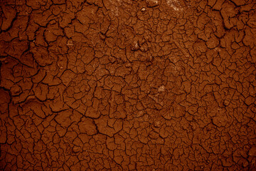 Dry cracked brown or red clay surface of the earth. The texture of the dry clay with cracks. Human footprints in the dry soil with faults.
