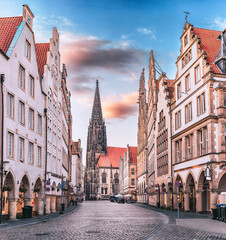 Scenic sunset view of Prinzipalmarkt square in Munster, Germany - without crowds of tourists at famous shopping street and tourist attraction. Saint Lamberti Tower at background. © EdNurg