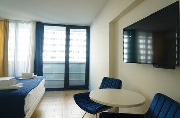 Luxury modern hotel room. Bedroom interior with curtains. bedroom with double bed, two blue armchairs and windows.