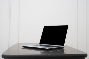 Blank gray  laptop screen on black wooden table. Cozy workplace at home. Mock up. Blank black laptop monitor on wooden table without decor elements for comfortable remote work. Mockup.