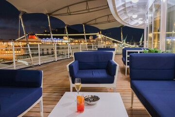 Champagne sparkling wine and cocktail longdrink on outdoor patio terrace deck of luxury cruiseship cruise ship liner yacht in port pre dinner drinks bar service	
