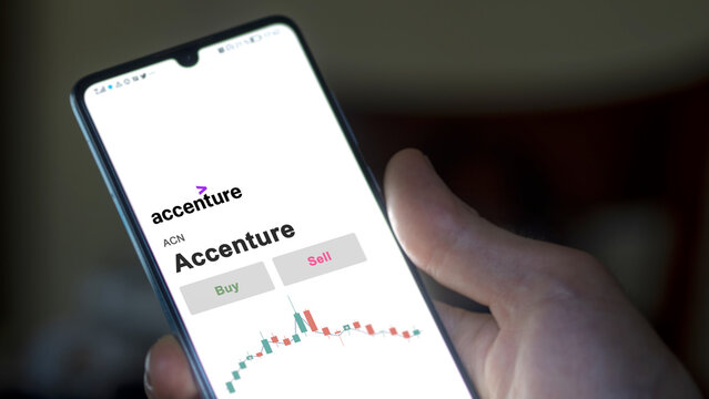 An investor's analyzing the Accenture ACN stock on screen. A phone shows the prices to invest