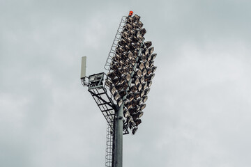 Stadium lights made of halogen bulbs in array on a concrete tower against a cloudy sky