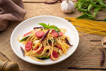 Stir fried Hot dog or sausage with Spaghetti with Dried Chili and garlic in white plate.Fusion food