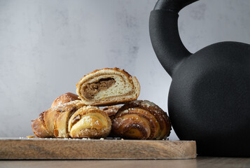 St. Martin's croissant and heavy gym kettlebell. Rogal marciński or świętomarciński. Traditional polish pastry with poppy-seed filling and nuts. Healthy fitness diet choice concept with copy space.
