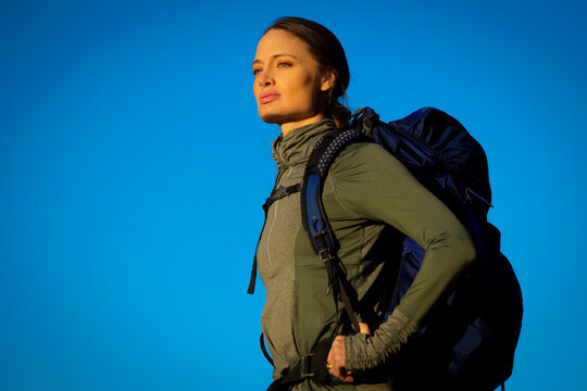 A woman with a backpack on looking into the distance