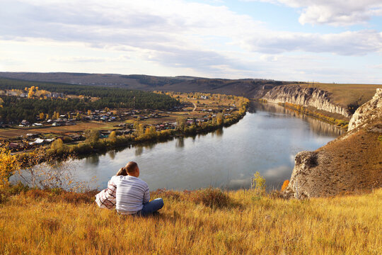 A married couple is sitting hugging on the riverbank
