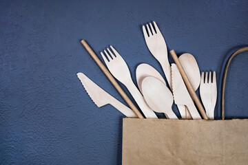 Disposable bamboo cutlery in a paper bag on a gray background. Flat lay.