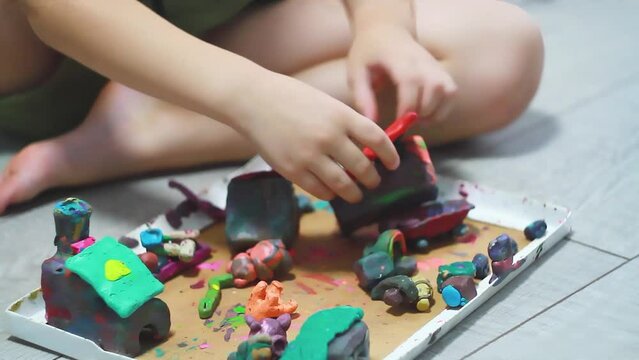 Child plays with clay. Clay sculpting in children's room.