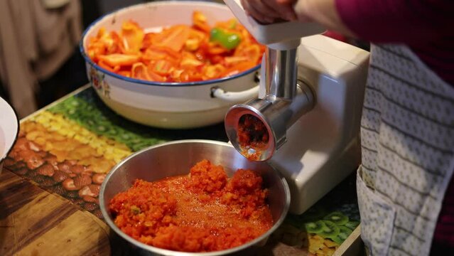 A woman grinds red pepper in a bowl with a mixer