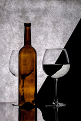 Still life with glasses and a brown bottle on a gray background