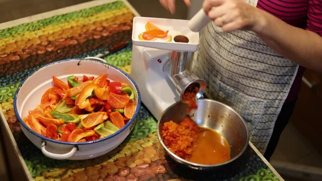 A woman grinds red pepper in a bowl with a mixer