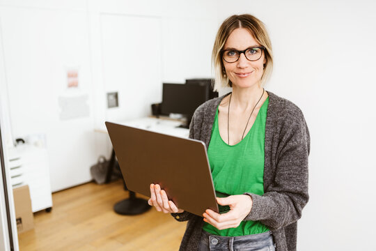 Young business woman with laptop looks at camera