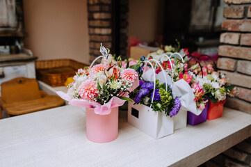 Cardboard baskets, packed boxes with colorful flowers are on a wooden table. Text, the word 