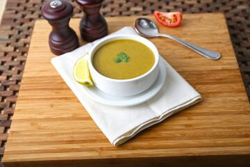 lentil Soup with spoon, lime slice and tomato served in bowl isolated on table side view of middle east food