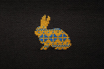 The symbol of the year 2023 is a rabbit embroidered with yellow and blue threads on a white fabric.