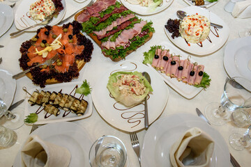 Different dishes with snacks on the festive table. A variety of food for guests at the reception.
