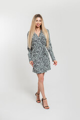 Fashionable happy beautiful woman with stylish elegant zebra dress with heels shoes walks on the white background in studio