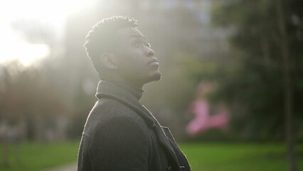 African young black man standing at park looking up in contemplation