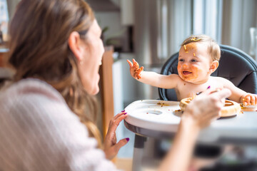Little baby girl eating her dinner with her mother