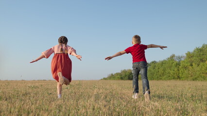 Children boy, girl play in park, Friends run together raising their hands, dream is to fly to...