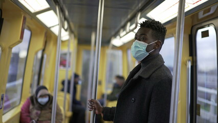 Fototapeta na wymiar African man standing in subway metro wearing coronavirus mask underground commute5