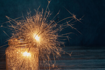 Christmas burning sparklers in a glass jar on wooden boards