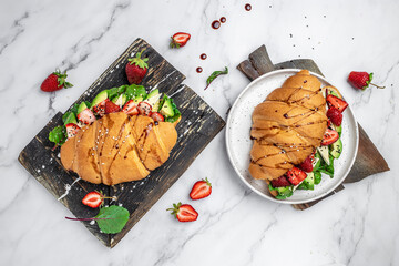 Sandwich Croissant with avocado, strawberries, brie camembert cheese, fresh salad in a whole wheat bread with seeds. Healthy diet concept. banner, menu, recipe, top view