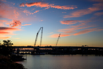 Fototapeta na wymiar Construction cranes working on the Arkansas River Bridge