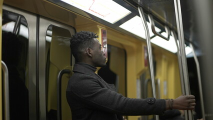 African man adjusting face mask while commuting on train holding bar handrail5