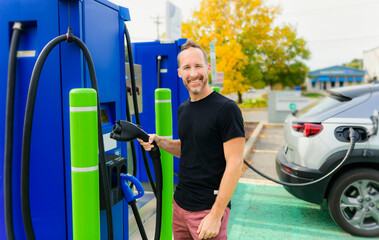 man inserts plug into the electric car charging socket