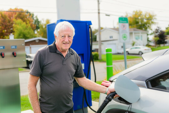 senior man inserts plug into the electric car charging socket