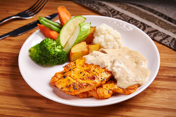 Creamy Grilled Chicken Breast with salad, tomato, cucumber and potato served in dish isolated on table side view of middle east food