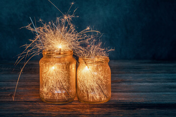 Christmas burning sparklers in a glass jar on wooden boards