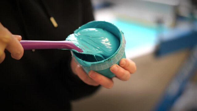 Mixing blue plastisol ink for screen printing using a purple spatula up-close shot