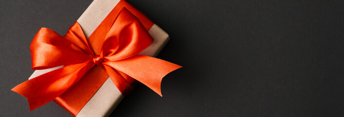 Banner made of Present box with red bow on black background. Flat lay, top view, copy space.