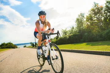 Tuinposter professional female cyclist in protective gear outdoors on a daytime © Louis-Photo