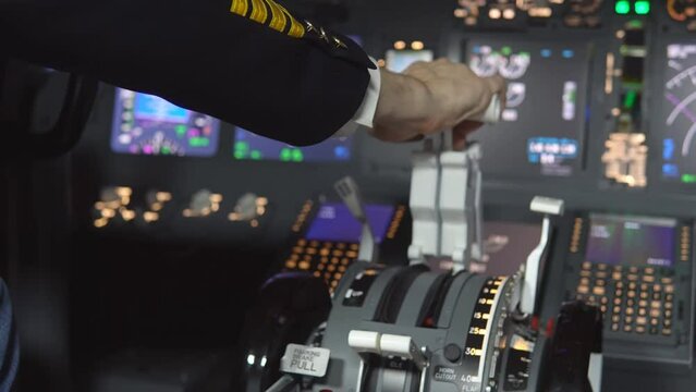 Close up of the pilot hand pressing the gas lever in the cockpit of the jet aircraft throttling engine power during takeoff.