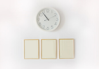 Empty photo frames with a clock on the white wall
