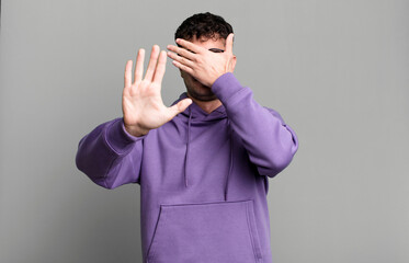 covering face with hand and putting other hand up front to stop camera, refusing photos or pictures